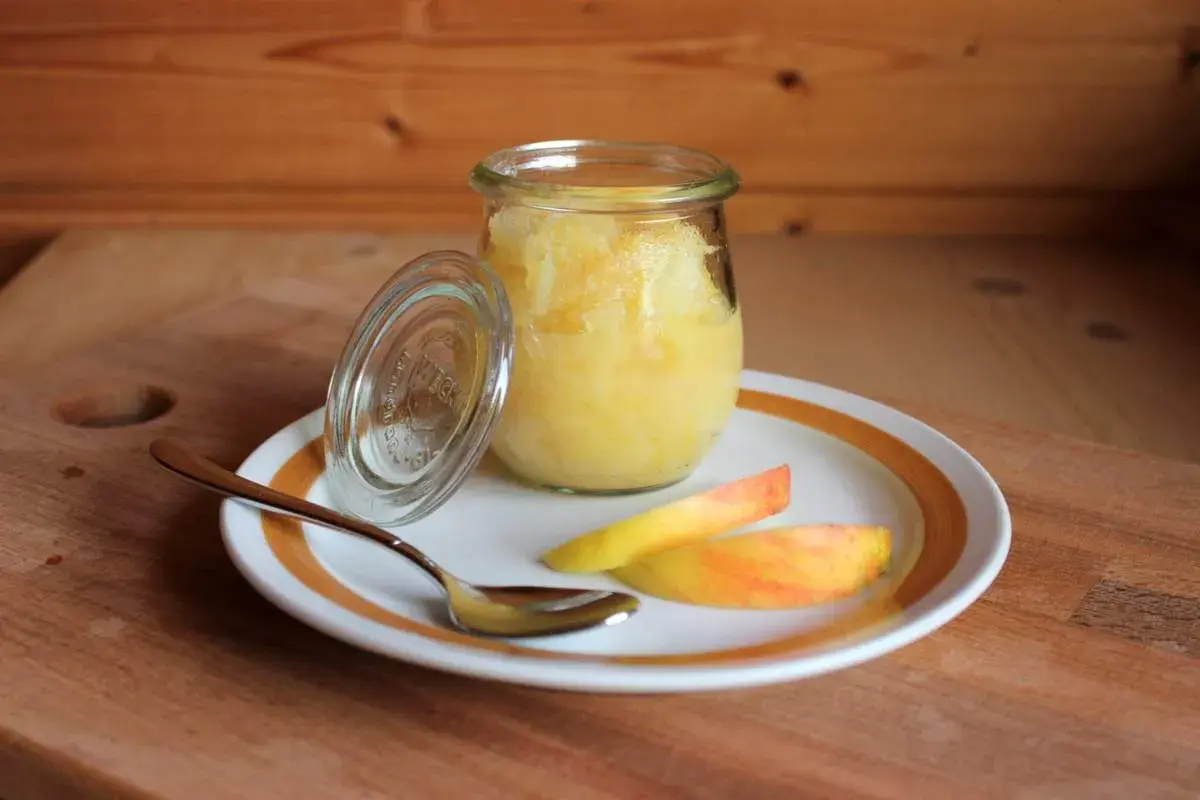 Glas mit selbstgemachtem Apfelmus, daneben Apfelspalten und ein Löffel. Perfekt zum Apfelmark selber machen!