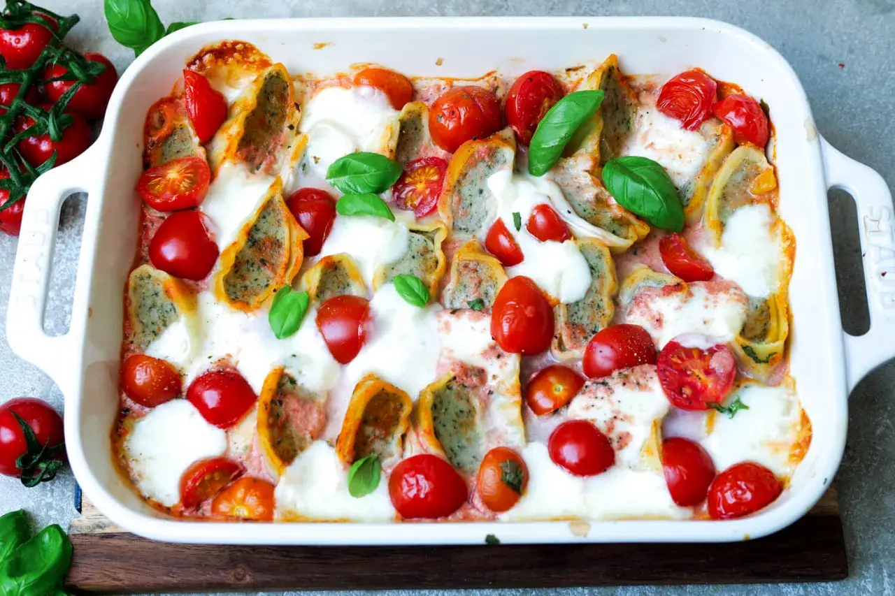 Herzhafter Maultaschen Auflauf mit Kirschtomaten und geschmolzenem Mozzarella, garniert mit frischem Basilikum.