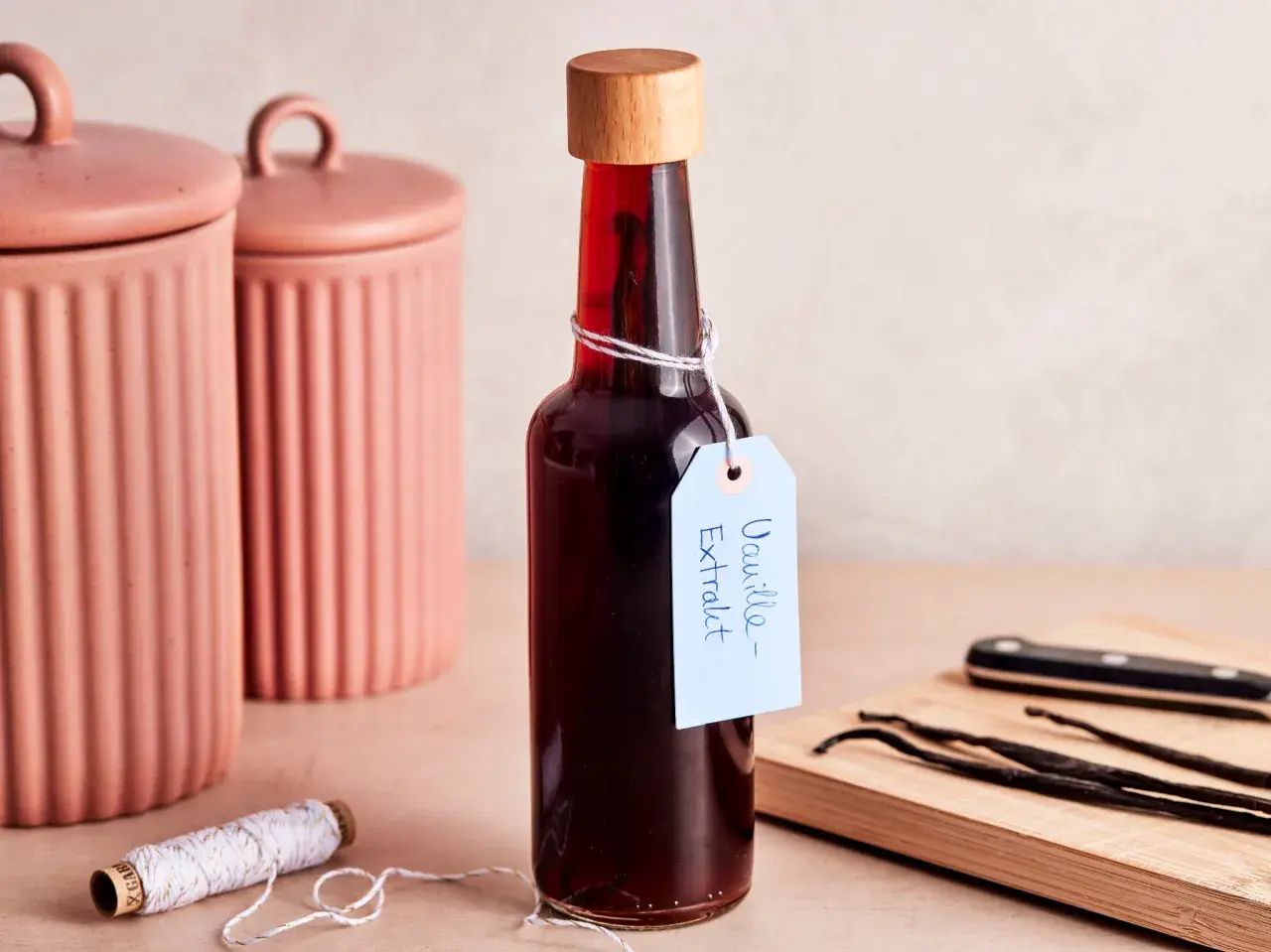 Flasche mit selbstgemachtem Vanilleextrakt, Vanilleschoten und Schnur.