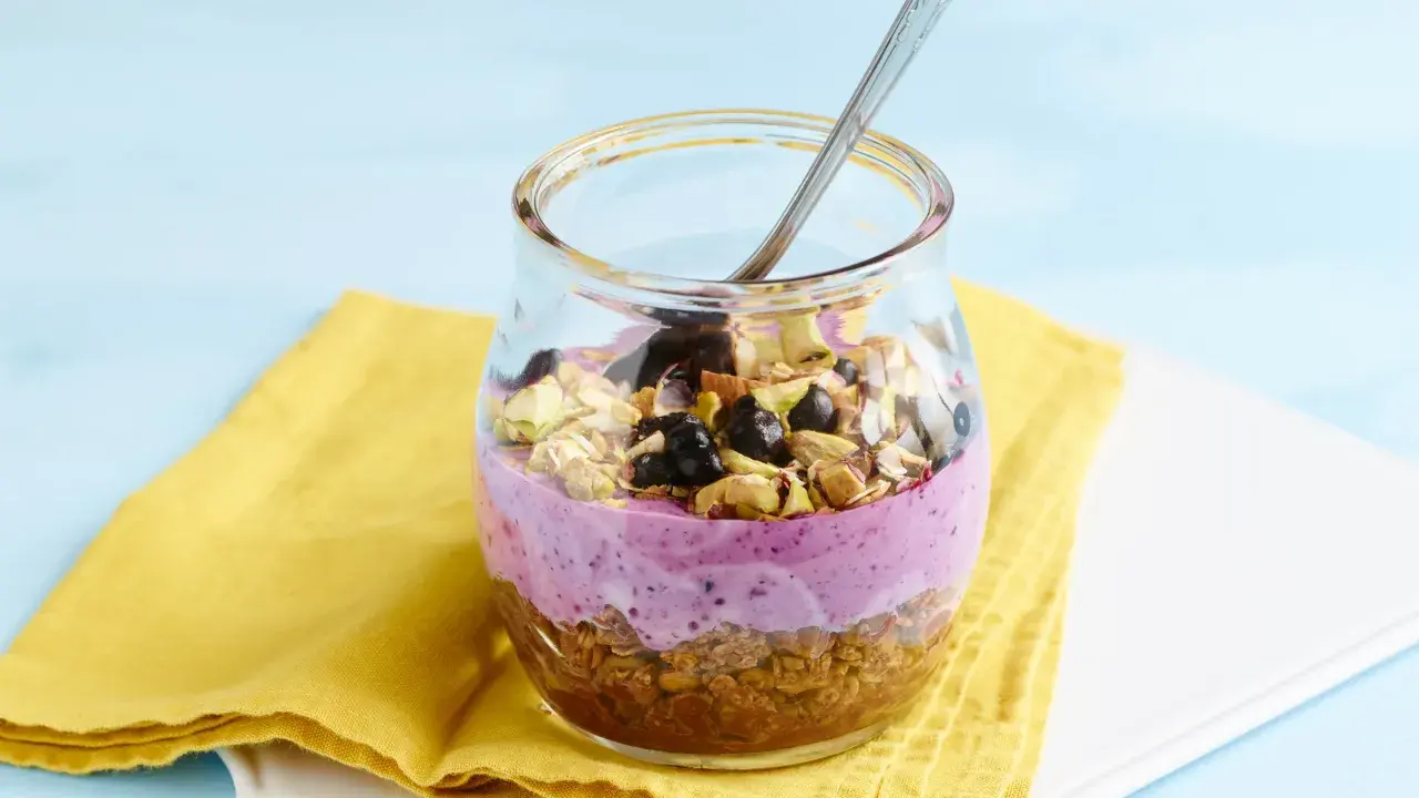 Ein Glas mit Joghurt, Beeren und Nüssen. Sojaflocken wie essen? Dieses leckere Frühstück ist eine tolle Option!