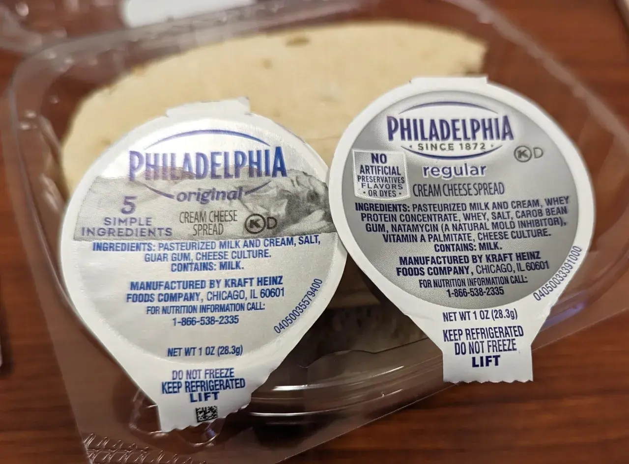 Zwei kleine Becher Philadelphia cream cheese deutsch, original und regular, in einer Plastikverpackung.