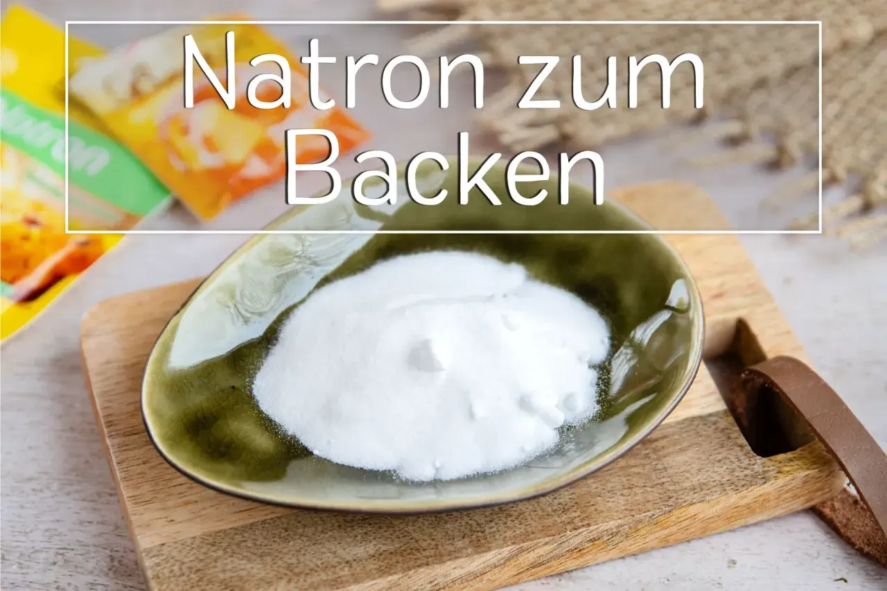 Eine Schale mit weißem Natron zum Backen steht auf einem Holzbrett. Im Hintergrund sind Packungen zu sehen.