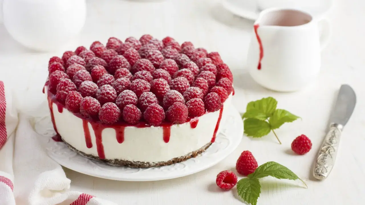 Ein köstlicher Kuchen ohne Backen, bedeckt mit frischen Himbeeren und Himbeersauce.