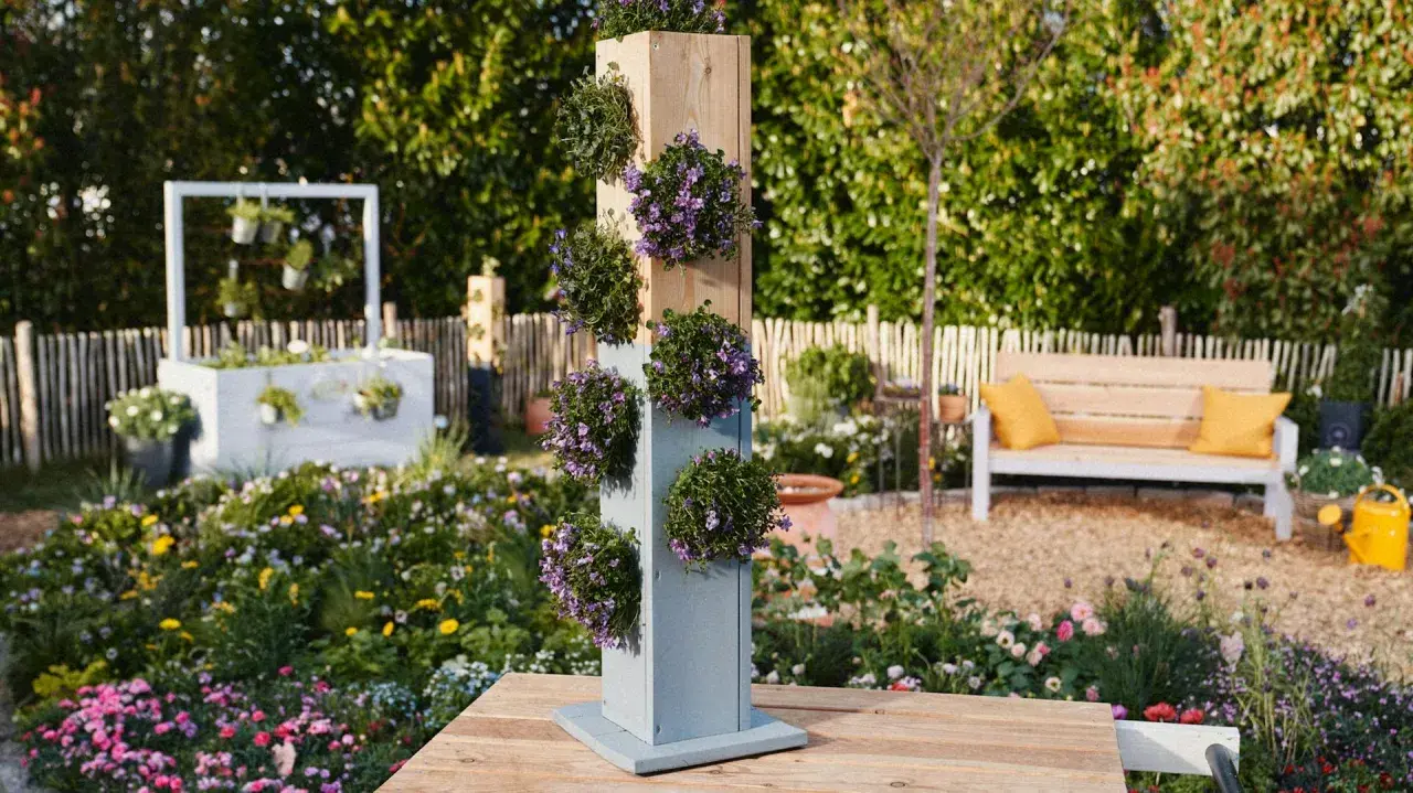 Ein vertikaler Pflanzturm mit lila Blüten, perfekt für alle, die einen Pflanzturm selber bauen möchten.