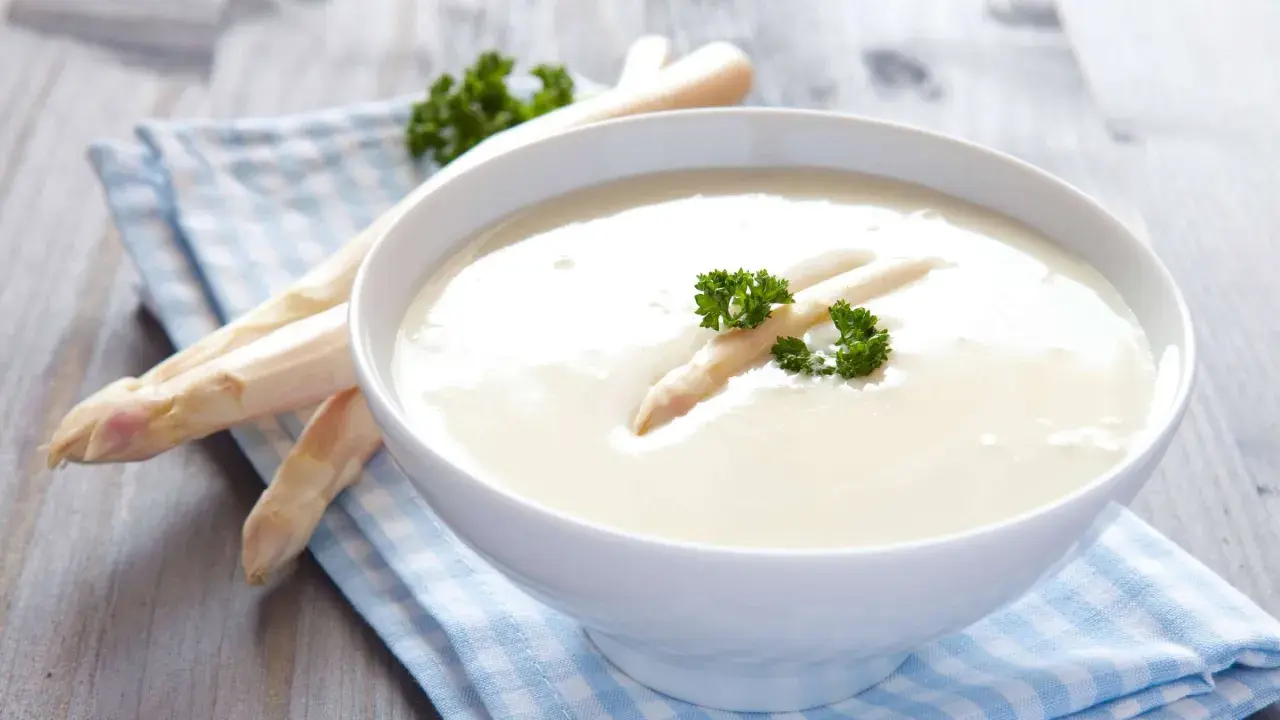 Cremige Spargelsuppe aus Spargelschalen, garniert mit einem Spargelspitz und Petersilie.