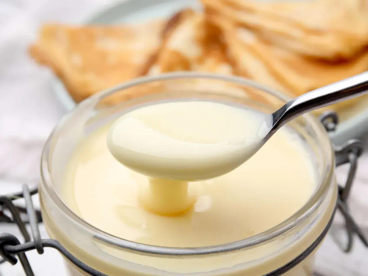 Cremige, selbstgemachte gezuckerte Kondensmilch in einem Glas, bereit zum Verfeinern von Desserts.