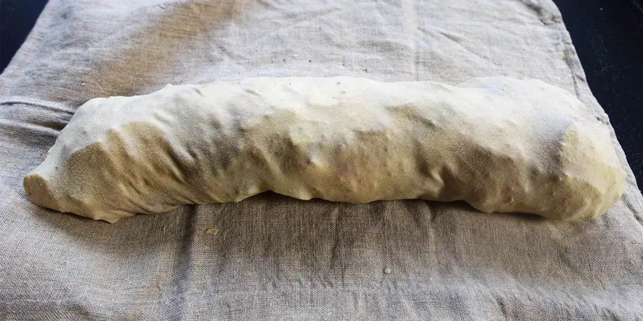 Ein roher Seitan-Strang, bereit zum Kochen, liegt auf einem Leinentuch. Das ist der erste Schritt, um seitan selber machen.