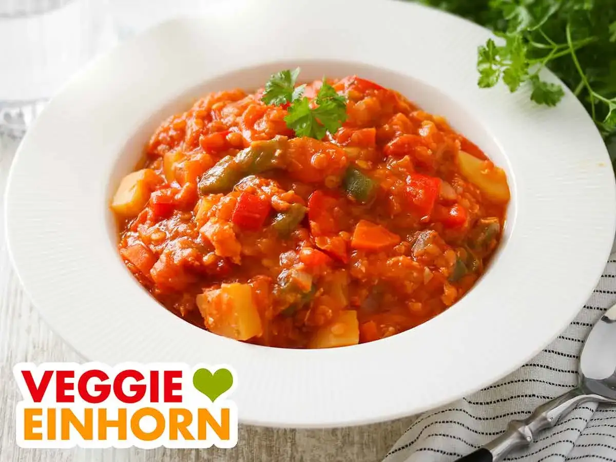 Herzhafter rote Linsen Eintopf mit Gemüse, garniert mit Petersilie. Ein köstliches Gericht für alle Veggie-Fans.