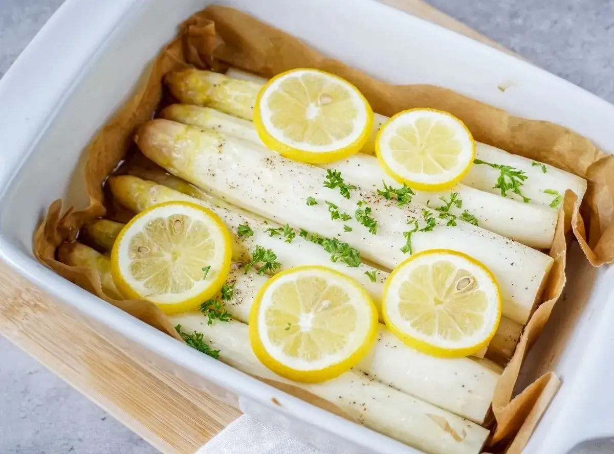 So einfach wie bereitet man Spargel zu: wei&szlig;e Spargelstangen mit Zitronenscheiben und Petersilie im Ofen gebacken.