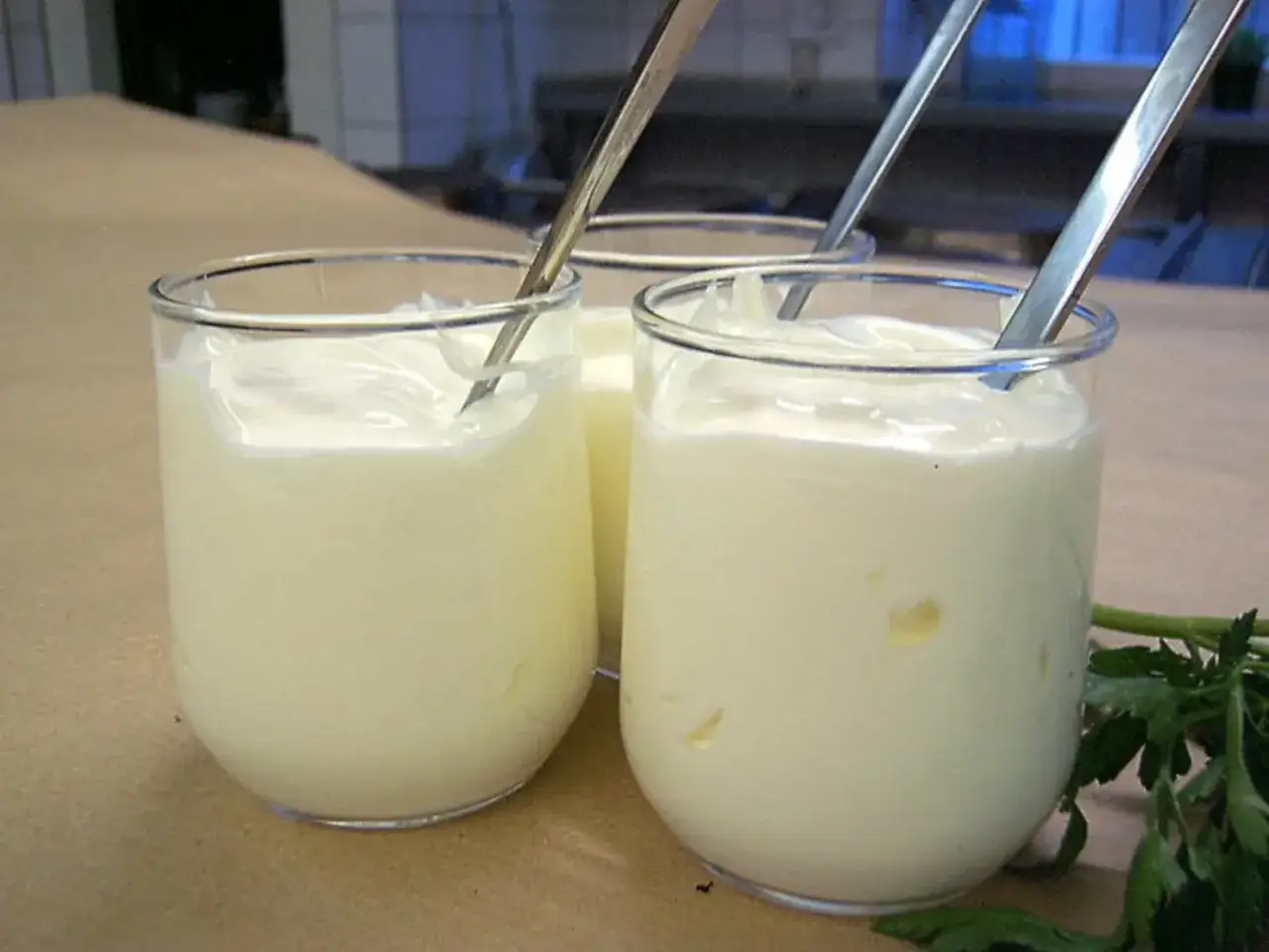 Drei Gläser mit selbstgemachtem Creme Fraiche, bereit zum Genießen. Ein Löffel in jedem Glas.