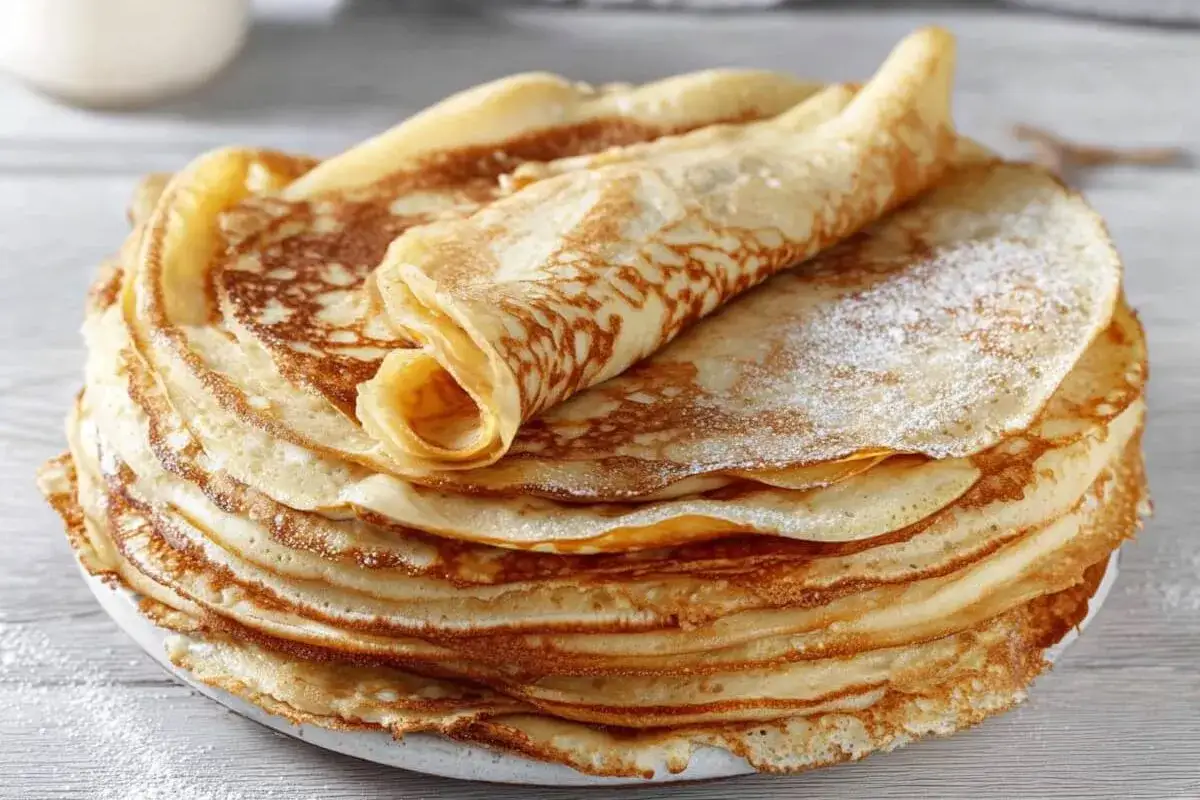 Ein Stapel goldbrauner Pfannkuchen, bestäubt mit Puderzucker. Dieses Pfannkuchen Rezept ist ein Klassiker.