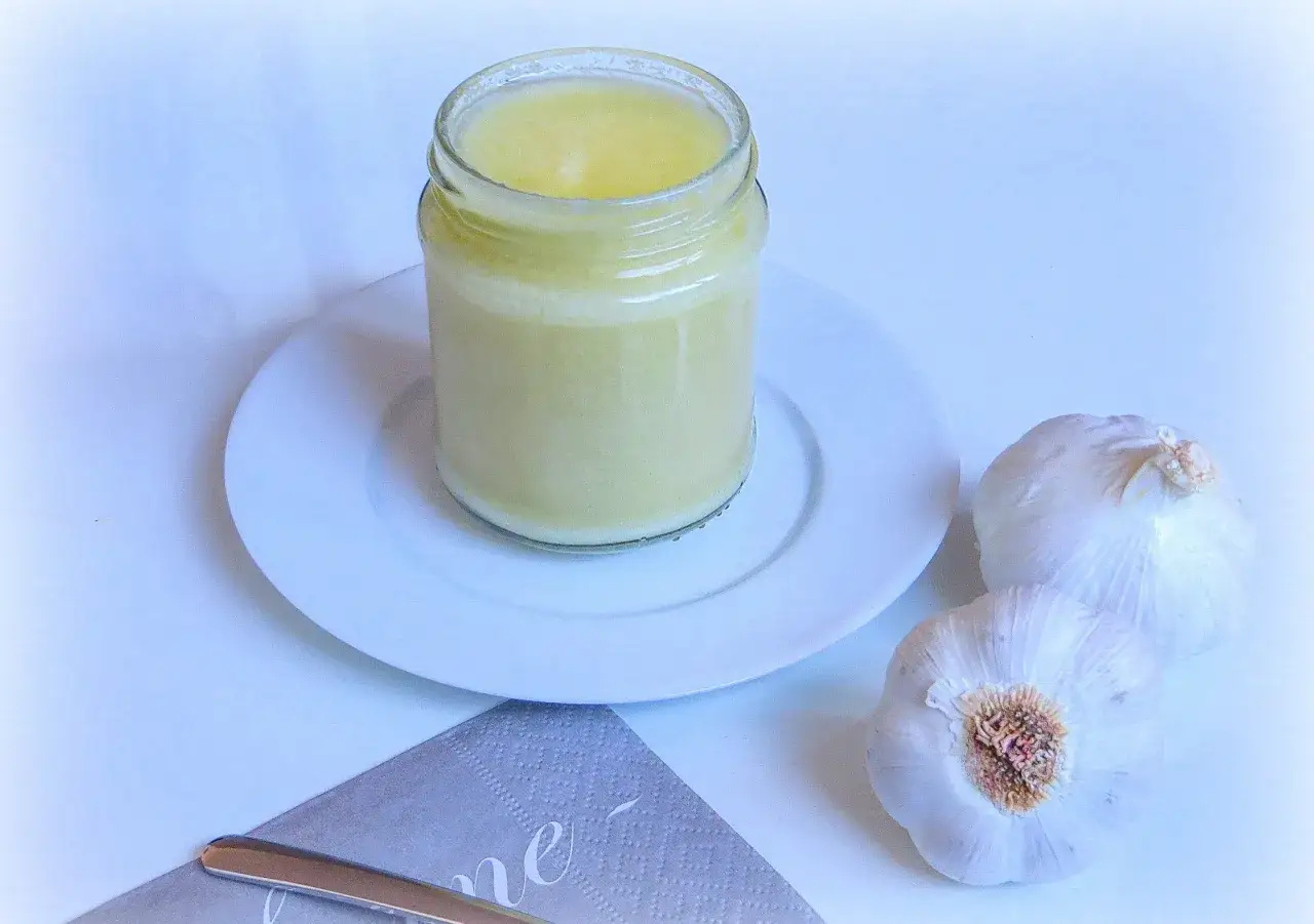 Glas mit cremiger Knoblauchpaste, daneben frische Knoblauchknollen. Ein einfaches Rezept f&uuml;r Knoblauchpaste.
