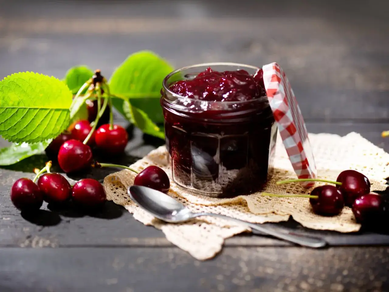 Frische Kirschen und ein Glas selbstgemachte Kirschmarmelade, bereit f&uuml;r ein k&ouml;stliches kirschmarmelade rezept.