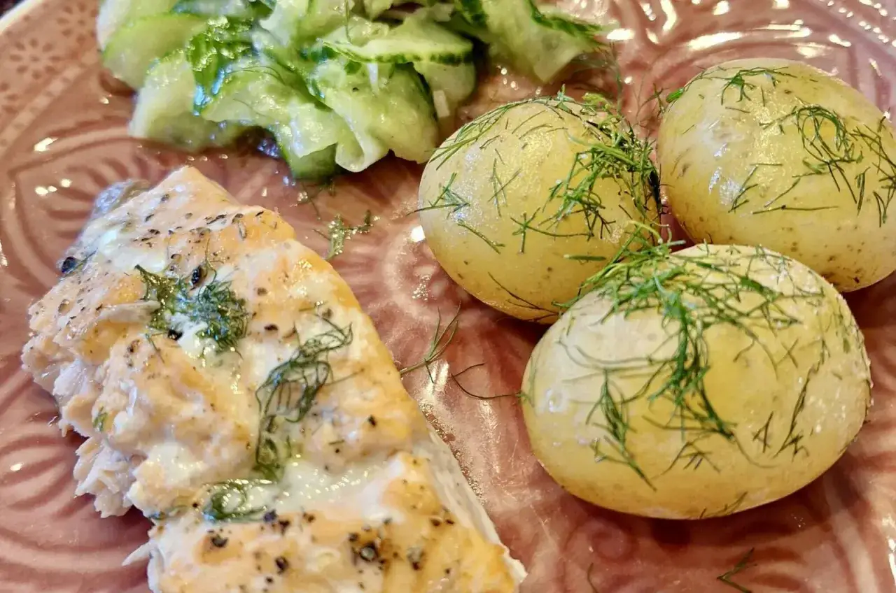 Saftiges Lachsforellenfilet aus dem Backofen, serviert mit Salzkartoffeln und Gurkensalat. Ein köstliches Gericht!