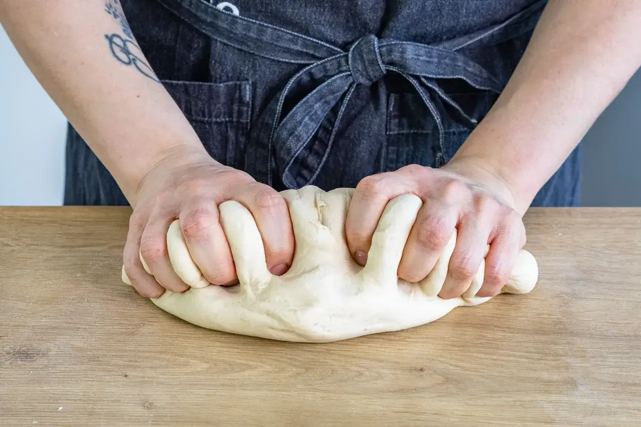 H&auml;nde kneten Brotteig auf Holztisch. Die Frage 