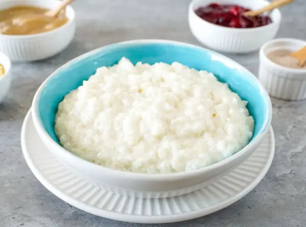 Cremiger Milchreis im blauen Schälchen, bereit für Zimt und Apfelmus. Ein einfaches Milchreis Rezept für gemütliche Momente.