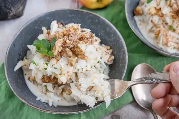Schwarzer Rettich Zubereitung: Ein cremiger Salat mit Walnüssen und Petersilie, serviert in einer Schüssel.